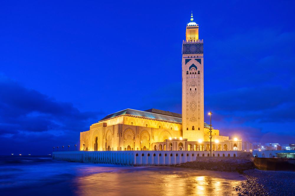 The magnificent Hassan II Mosque in Casablanca, beautifully lit against the night sky.